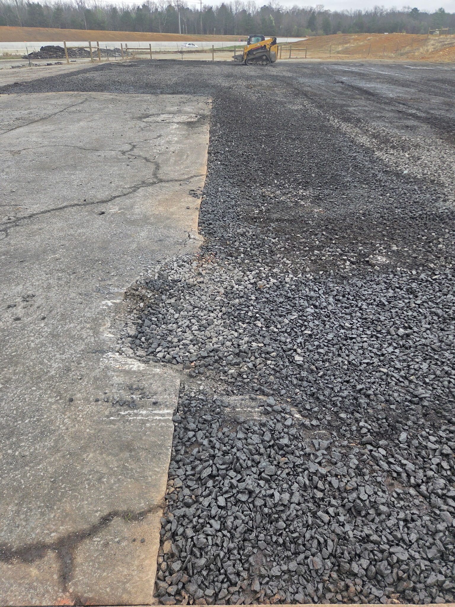 Later gravel and asphalt-edge condition at the east driveway.