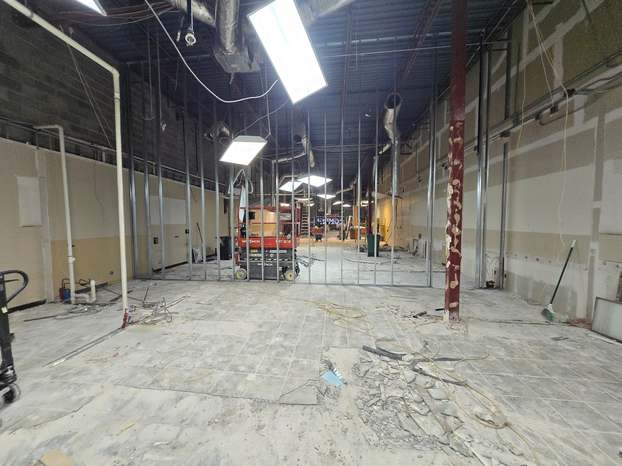 Austin retail interior with removed floor finishes, exposed overhead systems and metal-stud partition layout